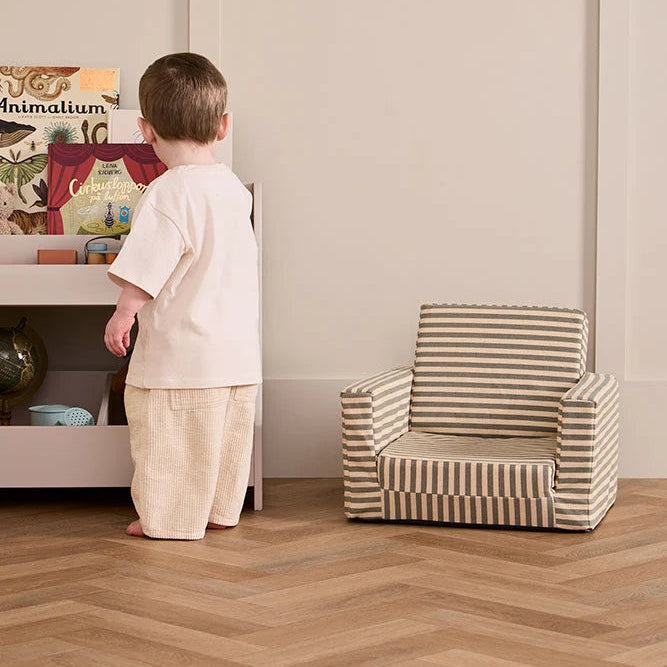 Bambino accanto alla Poltrona Pieghevole per Bambini Stripe Kids Concept 10001008 mentre esplora i libri.